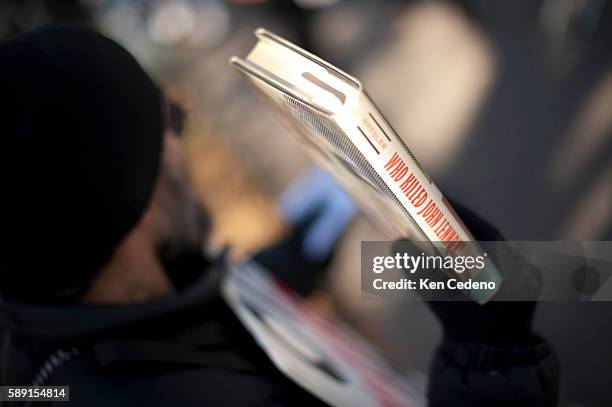 Man holds up a book "Who Killed John Lennon" as fans walk to Strawberry Fields in Central Park, New York, NY December 8, 2010. Lennon was murdered 20...