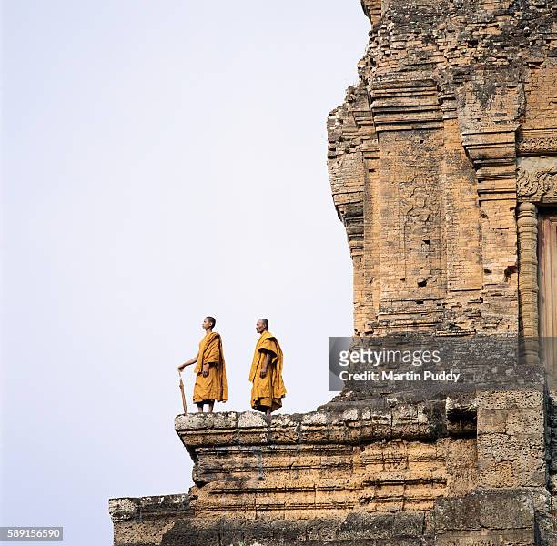 monks standing atop angkor wat - cambodian buddhist stock pictures, royalty-free photos & images