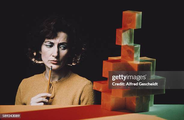 Woman contemplates a stack of building blocks, circa 1980.