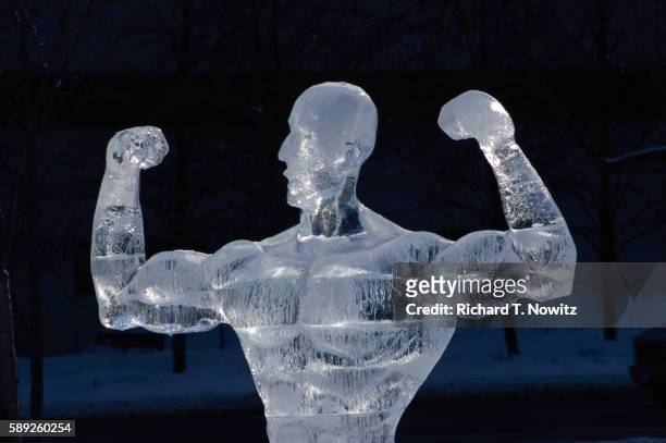 ice sculpture of man flexing muscles - ice sculpture stock-fotos und bilder
