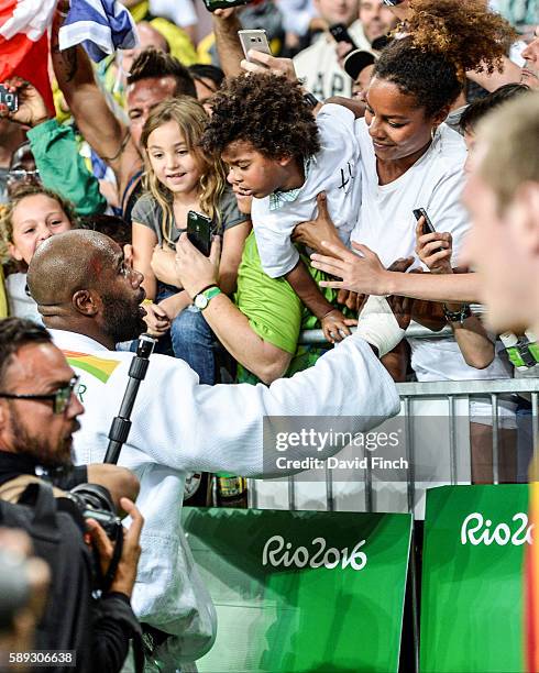 Olympic champion, Teddy Riner of France, tries hard to get to his son, Eden, and his partner, Luthna Plocus, while surrounded by dozens of...