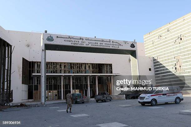 Member of Libyan pro-government forces walks in front of the Ouagadougou conference centre, where Islamic State group had set up base on August 13,...