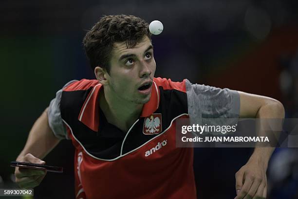 Poland's Jakub Dyjas eyes the ball as he serves in the men's team qualification round table tennis match against Japan at the Riocentro venue during...
