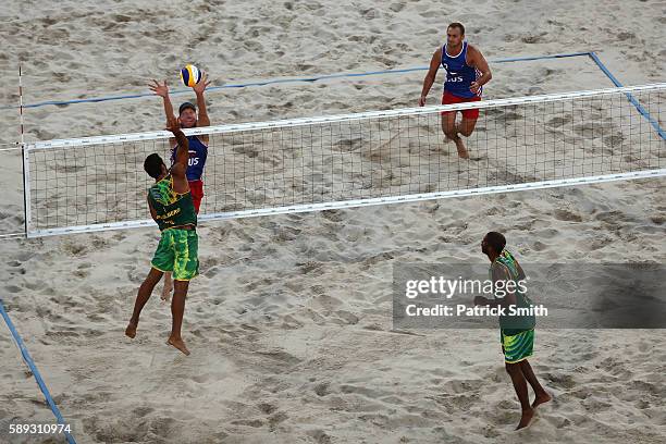 Pedro Solberg of Brazil spikes the ball against Nikita Liamin of Russia while Evandro Goncalves Oliveira Junior of Brazil and Dmitri Barsouk of...