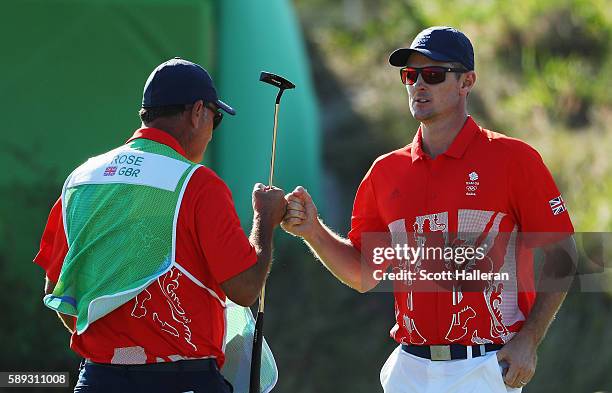 Justin Rose of Great Britain and his caddie Mark Fulcher celebrate a birdie on the 16th green during the third round of the golf on Day 8 of the Rio...