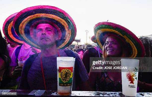 Man smokes as a woman looks on during the Rototom Sunsplash European Reggae Festival in Benicassim, Castellon province, on August 13, 2016. The...