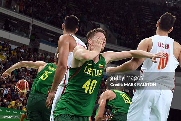 Lithuania's small forward Marius Grigonis holds his face and falls after being knocked during a Men's round Group B basketball match between Spain...