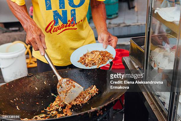 hands of the senior man cooking kway teow noodles at the street market, penang, malaysia - penang stock pictures, royalty-free photos & images