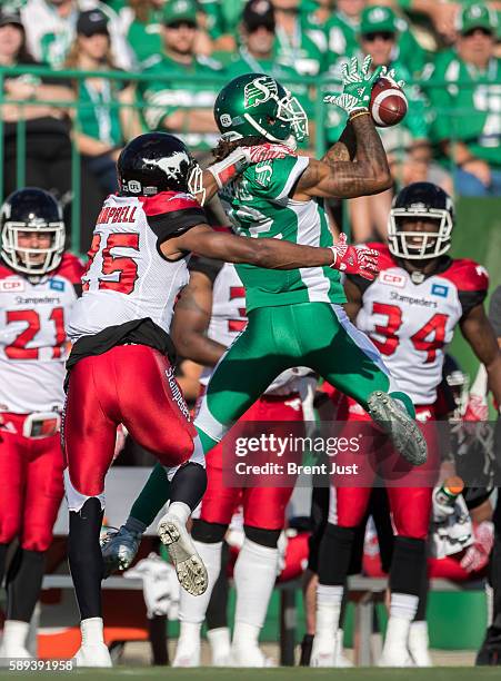 Naaman Roosevelt of the Saskatchewan Roughriders leaps to make a catch in front of Tommie Campbell of the Calgary Stampeders in first half action of...