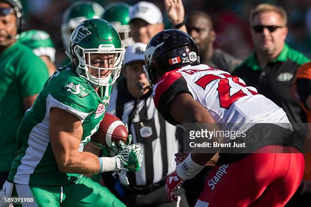 Rob Bagg of the Saskatchewan Roughriders looks to avoid Tommie Campbell of the Calgary Stampeders in first half action of the game between the...