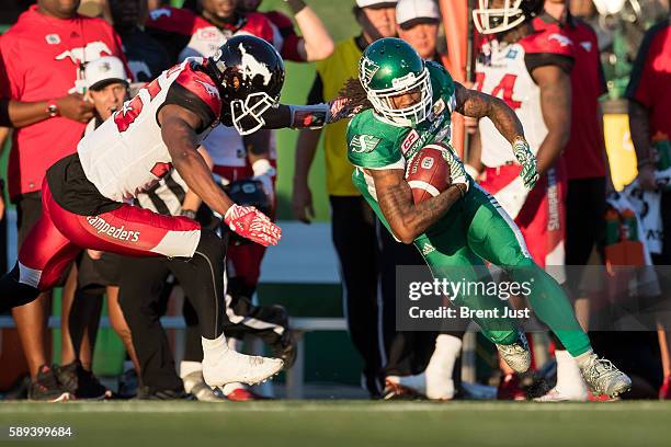 Naaman Roosevelt of the Saskatchewan Roughriders runs past Tommie Campbell of the Calgary Stampeders after a catch in the game between the Calgary...