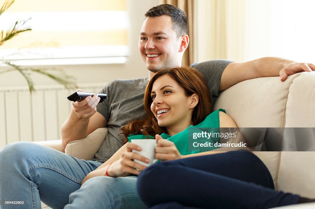 Jeune couple se relaxant sur un canapé et regardant la télévision ensemble