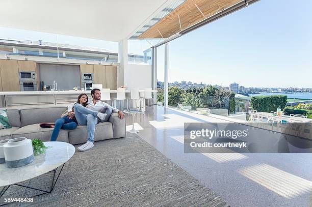 couple sitting in a modern open plan house. - apartment australia stockfoto's en -beelden