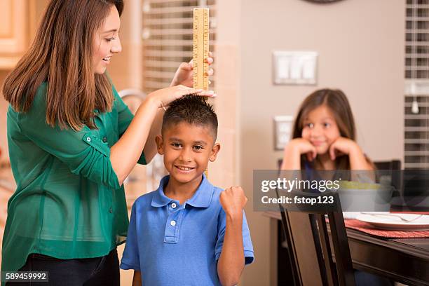 mother measures growing son's height with yard stick. - meter stick stock pictures, royalty-free photos & images