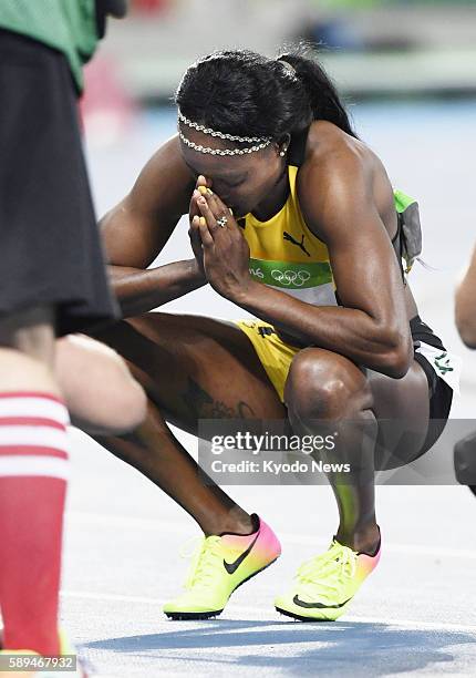 Jamaican sprinter Elaine Thompson crouches down and places her hands together after winning the women's 100-meter final in the athletics competition...