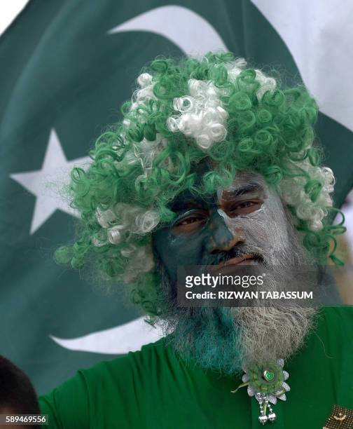 Face-painted Pakistani man attends a ceremony to mark the Independence Day celebrations at the mausoleum of founding father, Quaid-e-Azam Mohammad...