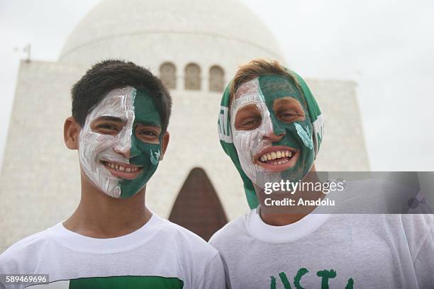 Pakistani boys with their faces painted in national colors are seen during a ceremony marking Pakistan's 69th Independence Day at the founder of...