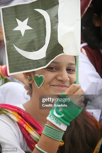 Pakistani girl holds a Pakistani flag during a ceremony marking Pakistan's 69th Independence Day at the founder of Pakistan Muhammad Ali Jinnah's...