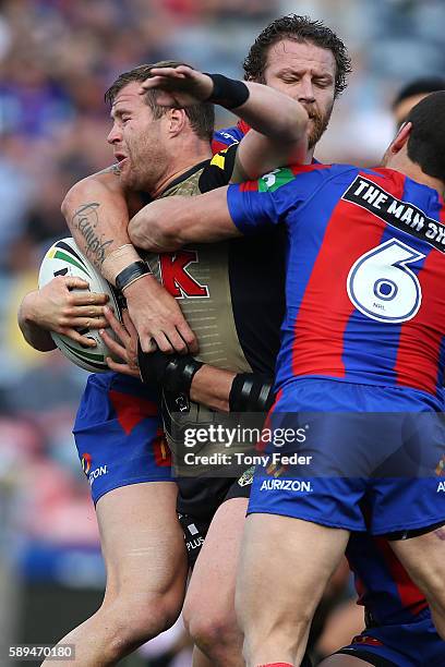 Trent Merrin of the Panthers is tackled by the Knights defence during the round 23 NRL match between the Newcastle Knights and the Penrith Panthers...