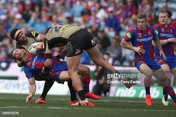 Tyler Randell of the Knights is tackled by Sitaleki Akauola of the Panthers during the round 23 NRL match between the Newcastle Knights and the...