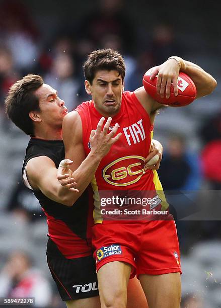 Matt Rosa of the Suns is tackled by Mathew Stokes of the Bombers during the round 21 AFL match between the Essendon Bombers and the Gold Coast Suns...