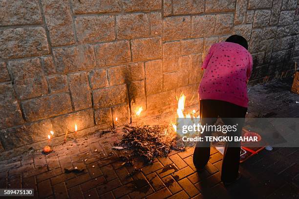 Local resident burns paper offerings in an alleyway near a local temple during Yu Lan or Hungry Ghost Festival in Hong Kong on August 14, 2016. The...