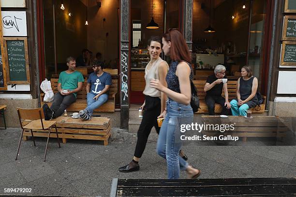 People sip coffee at a cafe in Mariannenstrasse in Kreuzberg district on a warm summer afternoon on August 13, 2016 in Berlin, Germany. While fall...