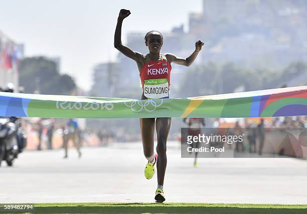 Kenya's Jemima Jelagat Sumgong raises her arms in victory as she crosses the finish line of the Women's Marathon during the athletics event at the...