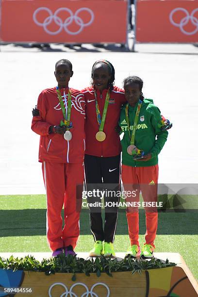 Bahrain's Eunice Jepkirui Kirwa Kenya's Jemima Jelagat Sumgong and Ethiopia's Mare Dibaba pose during the podium ceremony for the Women's Marathon...