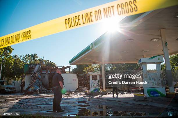 Police officer stands guard in front of the damage to the BP gas station after rioters clashed with the Milwaukee Police Department protesting an...