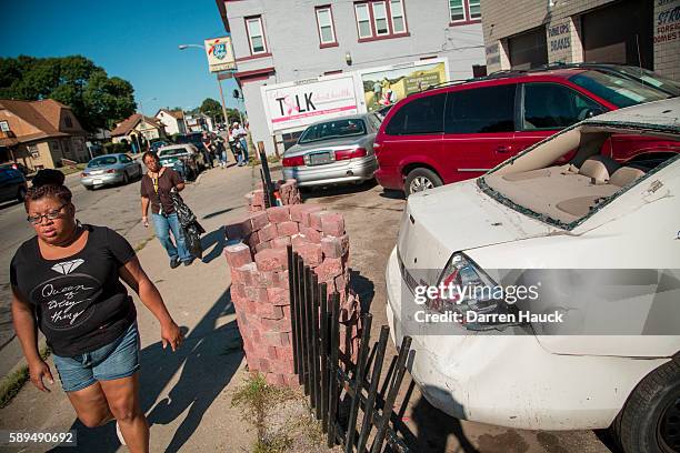 Volunteers walk down the street helping to clean up the damage after rioters clashed with the Milwaukee Police Department protesting an officer...