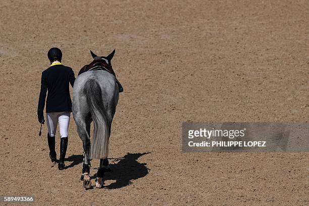 Italy's Cassio Rivetti leaves after falling during the equestrian's jumping individual and team qualifier event of the Rio 2016 Olympic Games at the...