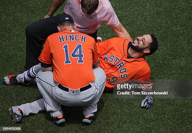 Marwin Gonzalez of the Houston Astros reacts after being hit by pitch as manager A.J. Hinch and the trainer tend to him in the first inning during...