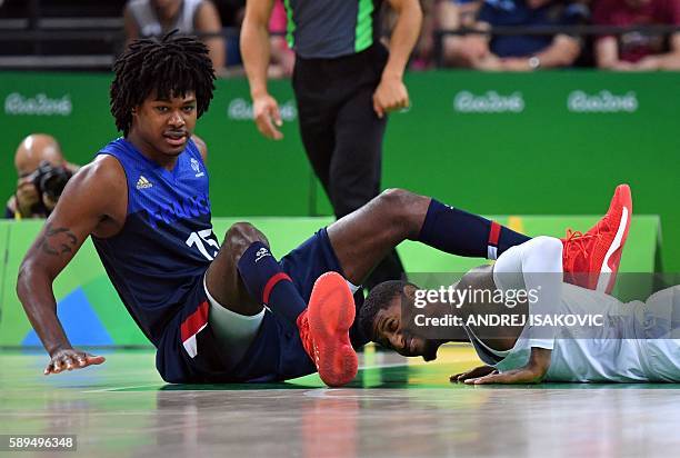 France's small forward Mickael Gelabale and USA's guard Paul George fall during a Men's round Group A basketball match between USA and France at the...