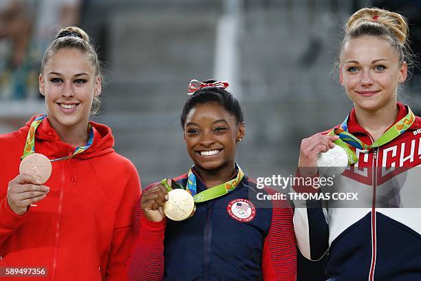 Russia's Maria Paseka, US gymnast Simone Biles and Switzerland's Giulia Steingruber celebrate on the podium for the women's vault event final of the...