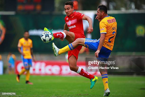 Israel Jimenez of Tigres struggles for the ball with Carlos Rodriguez of Toluca during the 5th round match between Toluca and Tigres UANL as part of...