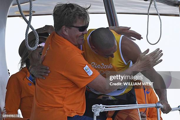 Netherlands' Dorian Van Rijsselberghe is congratulated by Netherland's King Willem-Alexander after he won the RS:X Men sailing final race on...