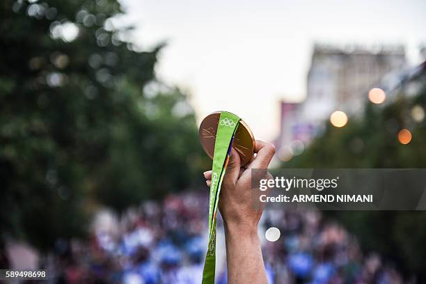 Kosovo's judoka Majlinda Kelmendi shows her gold medal to the supporters during a welcoming ceremony in Pristina on August 14, 2016. Majlinda...