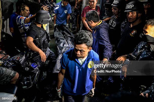 Workers from a funeral parlor, escorted by armed guards, carry out a corpse from the Paranaque city jail where a grenade blast killed 10 inmates, 8...