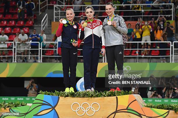 Gymnast Madison Kocian, Russia's Aliya Mustafina and Germany's Sophie Scheder celebrate on the podium of the women's uneven bars event final of the...