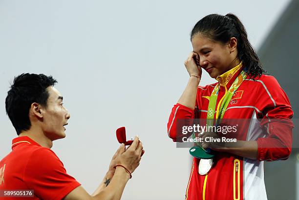 Chinese diver Qin Kai proposes to silver medalist He Zi of China on the podium during the medal ceremony for the Women's Diving 3m Springboard Final...