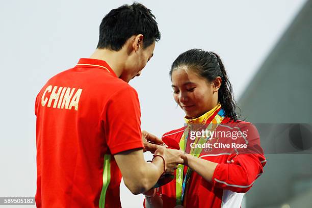 Chinese diver Qin Kai proposes to silver medalist He Zi of China on the podium during the medal ceremony for the Women's Diving 3m Springboard Final...