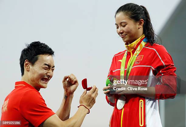 Chinese diver Qin Kai proposes to silver medalist He Zi of China on the podium during the medal ceremony for the Women's Diving 3m Springboard Final...