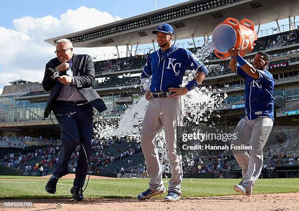 Fox Sports announcer Joel Goldberg gets out of the way as Salvador Perez of the Kansas City Royals pours water on teammate Paulo Orlando to celebrate...