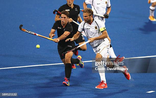 Nick Wilson of New Zealand is challenged by Moritz Furste during the Men's hockey quarter final match between the Germany and New Zealand on Day 9 of...