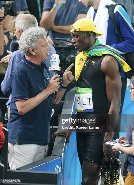 Usain Bolt of Jamaica reacts after his victory with presentator Neslson Monfort of france after the Athletics Men's 100m at Olympic Stadium on August...