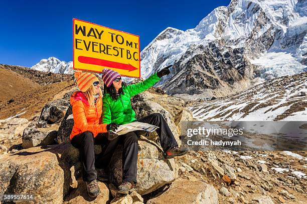 mulheres jovens a estudar mapa seguinte para poste de sinalização, nepalêsname himalaias - campo base do monte everest imagens e fotografias de stock