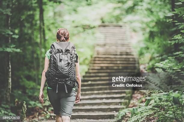woman hiking trekking with backpack on footpath in forest - following behind stock pictures, royalty-free photos & images