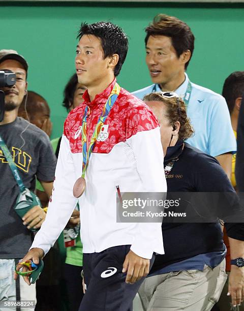 Japan's Kei Nishikori stands with his bronze medal, with tennis commentator Shuzo Matsuoka in the background, at the medal ceremony for the Rio de...