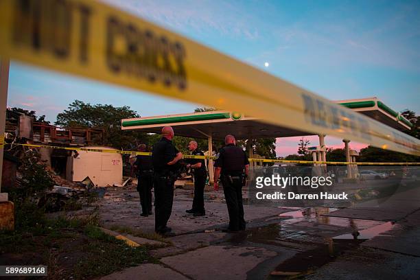 Police officers stand guard as crowds gather for a second night near the BP gas station that was burned after an officer-involved killing August 14,...